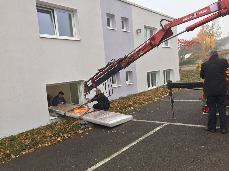 Ladekran hebt eine schwere Last durch ein Fenster ins Erdgeschoss